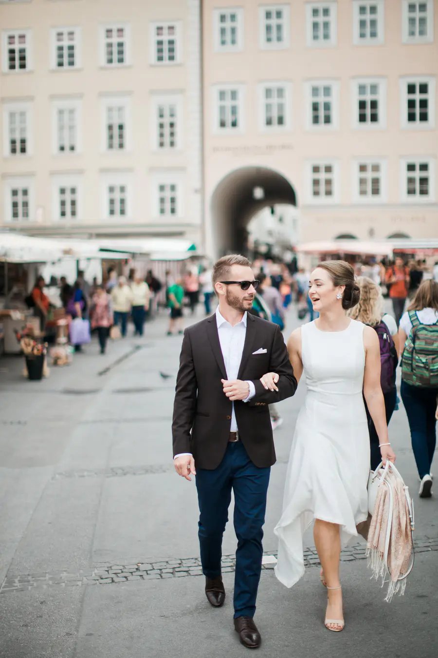 Authentische Editorial-Hochzeitsreportage in Salzburg: Brautpaar genießt die Sonne in den lebendigen Gassen der Salzburger Altstadt. Einzigartiges Storytelling, das Freude und urbane Atmosphäre perfekt einfängt. Exklusive Hochzeitsfotografie in Österreich im High-Fashion-Stil von Marek & Klára.