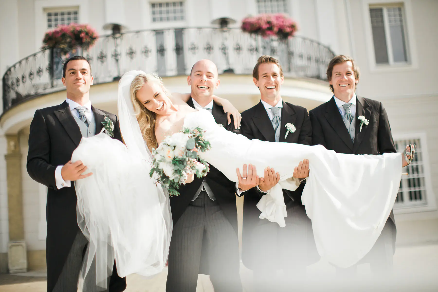 Lustige Hochzeitsmomente im Schloss: Lächelnde Groomsmen heben die Braut hoch. Authentische Hochzeitsreportage und spontane Augenblicke bei einer Schlosshochzeit. Professionelle Hochzeitsfotografie in Österreich und der Slowakei von Still and Motion Pictures.