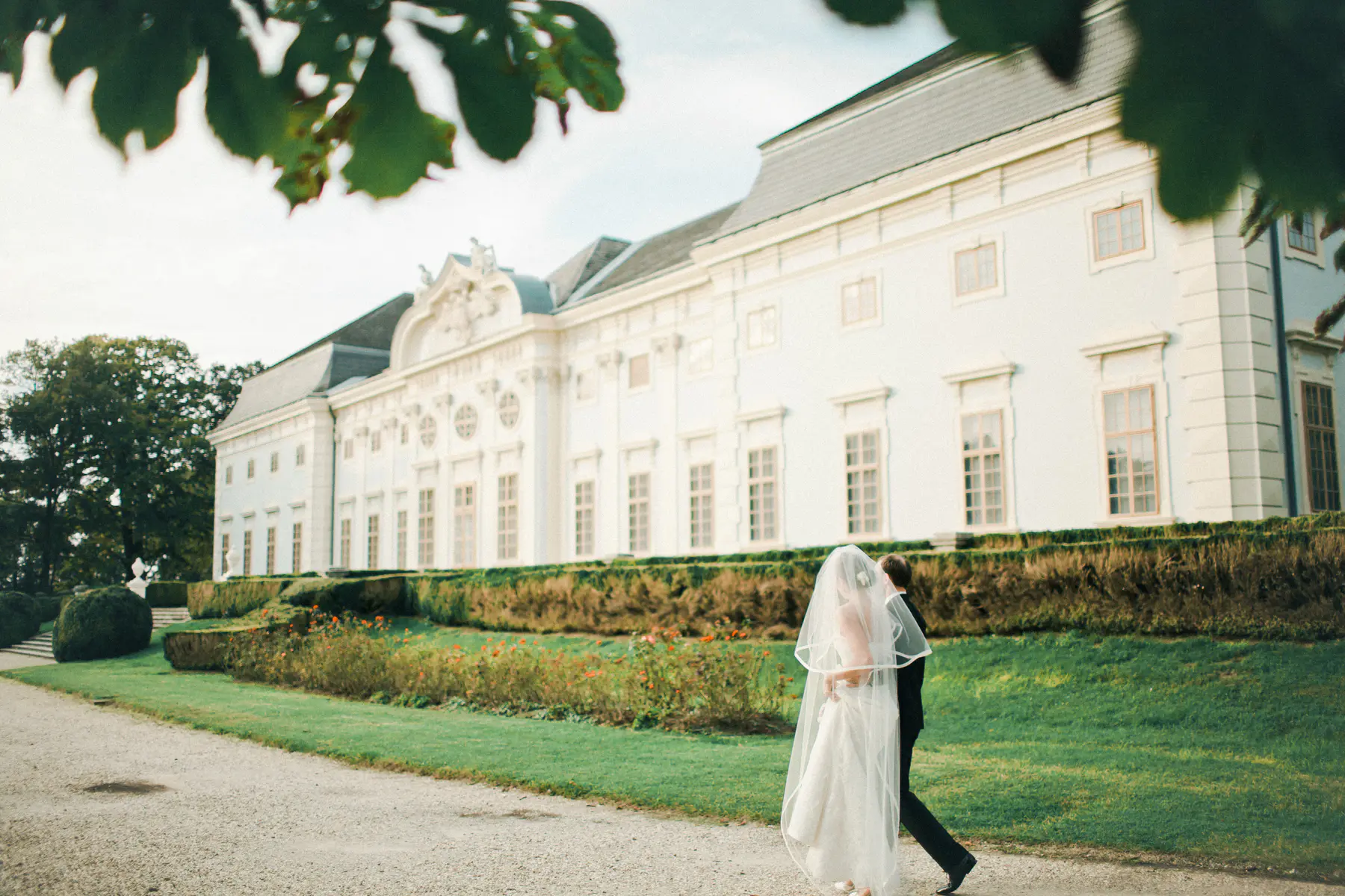 Elegantes Brautpaar im Barockgarten von Schloss Halbturn. Exklusive Hochzeitsfotografie im Burgenland und Wien. Klassische Hochzeitsreportage vor der historischen Kulisse eines der schönsten Barockschlösser Österreichs. Hochwertige Hochzeitsfotos und Filme von Still and Motion Pictures.