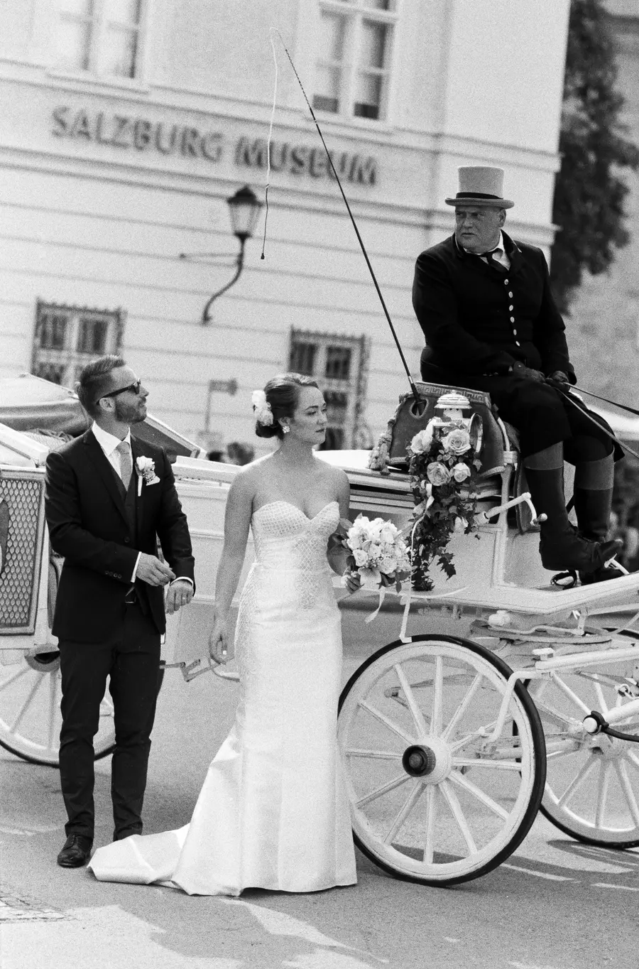 Bride and groom at city center got of horse drawn carriage in Salzburg analog B&W shot | wedding packages section