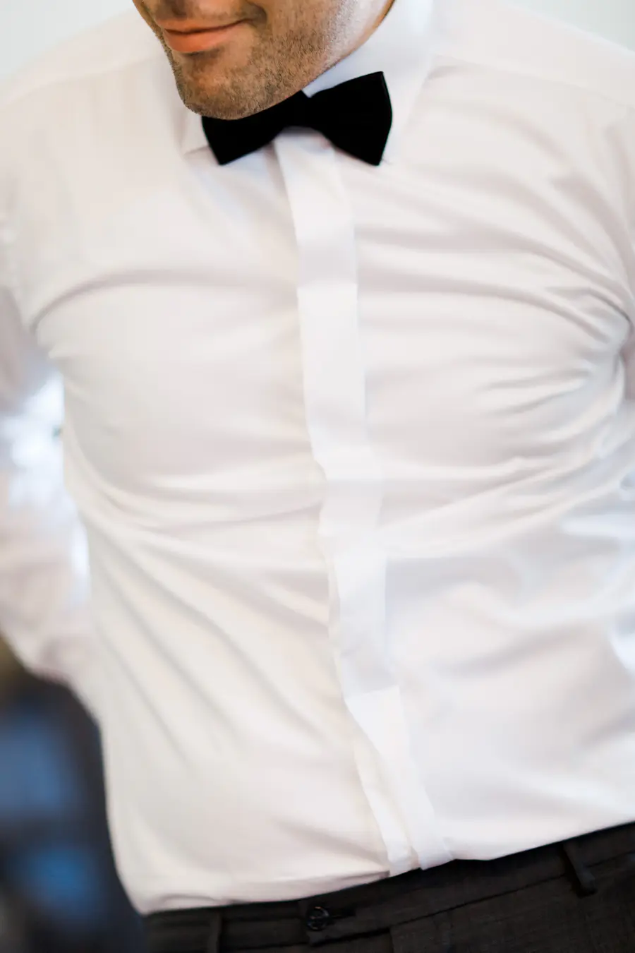Groom wearing a white dress shirt and black bow tie.