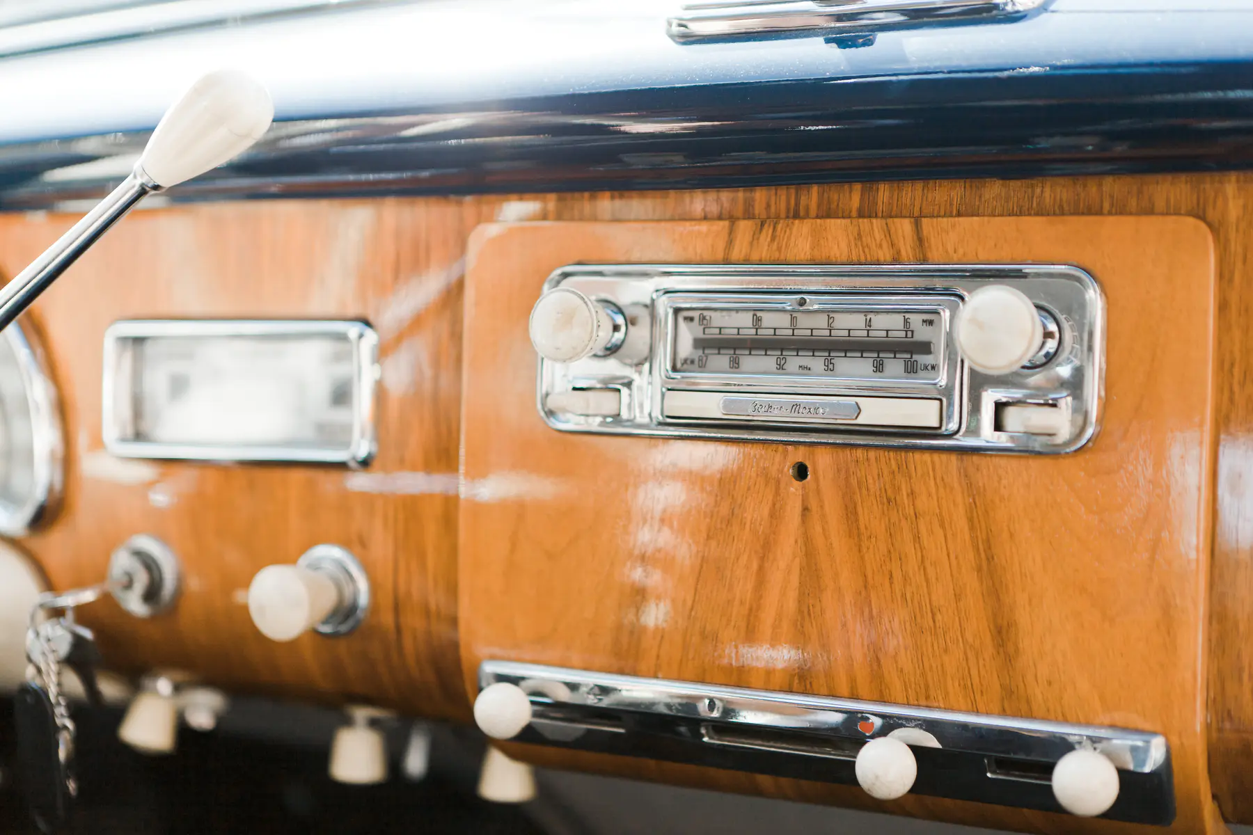 Close-up shot of a vintage car's wooden dashboard with a classic radio and chrome accents.