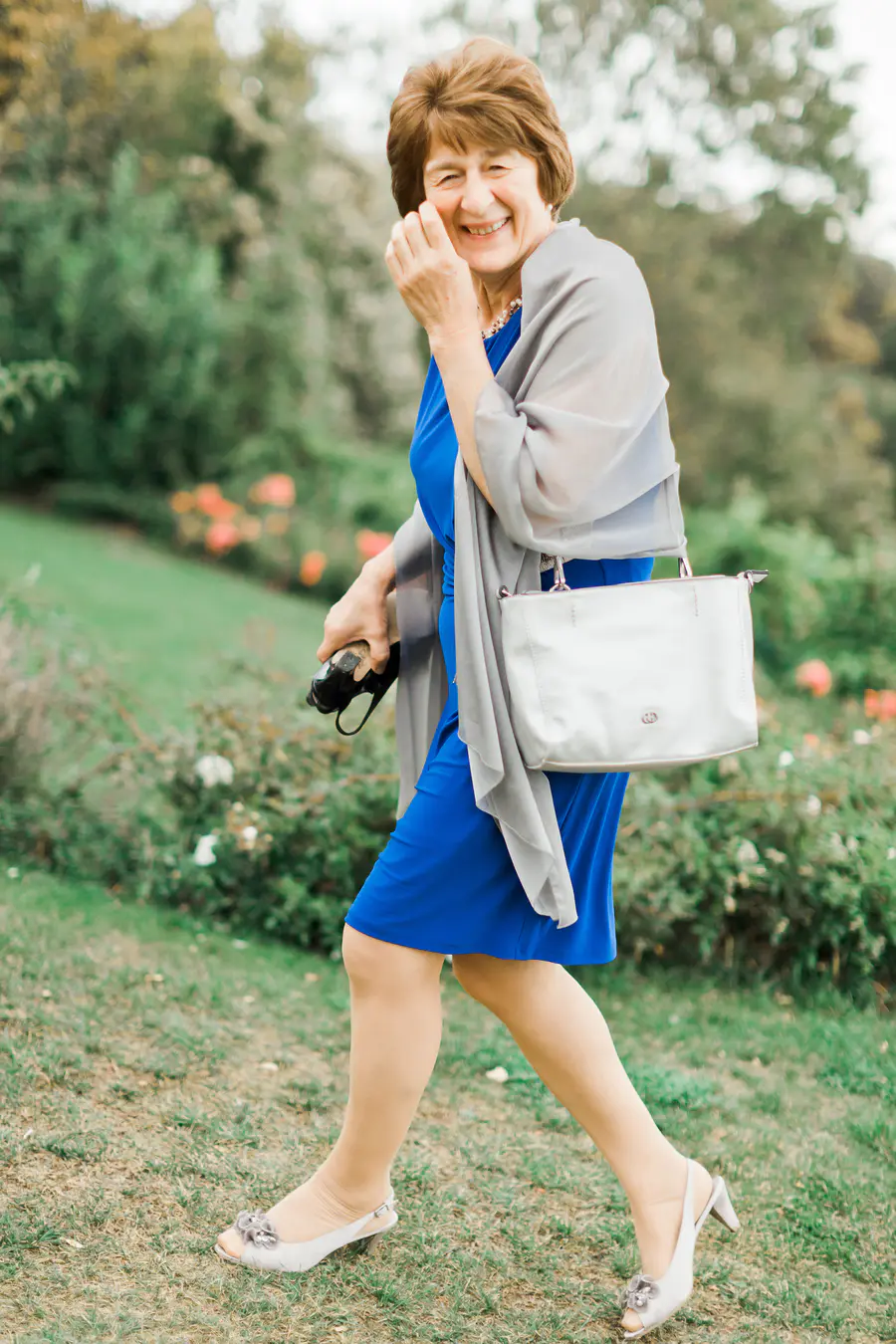 Smiling woman in blue dress walking in a garden during wedding at Weingut Reisenberg in Vienna