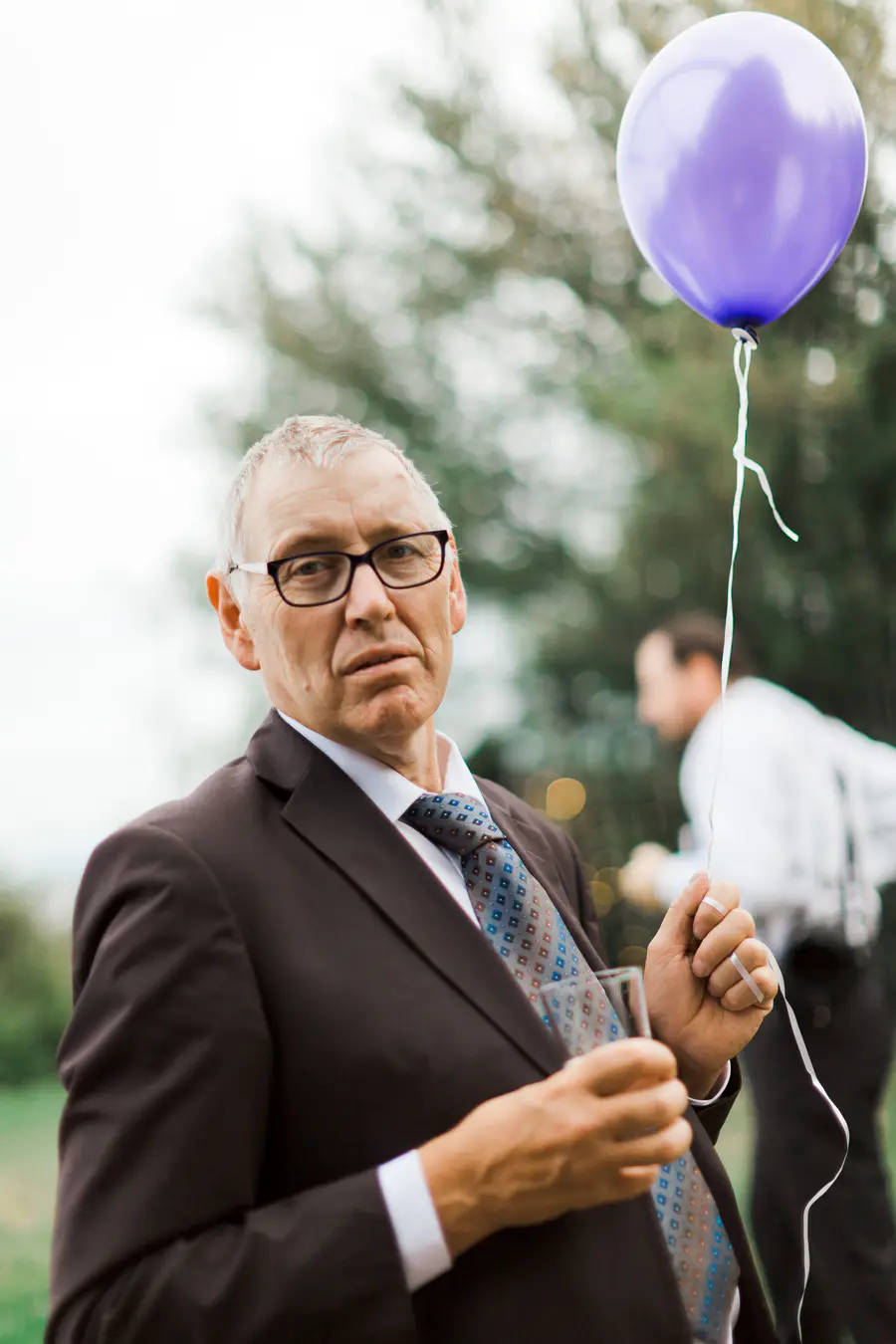 Wedding photo on a man holding purple baloon.