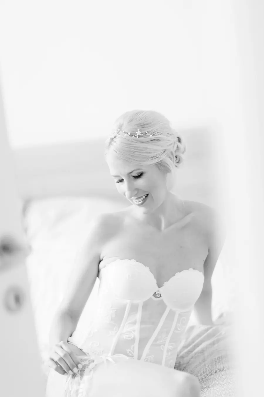 A black and white, medium shot shows a smiling bride wearing a strapless corset and a delicate tiara.Wedding photograhers Vienna