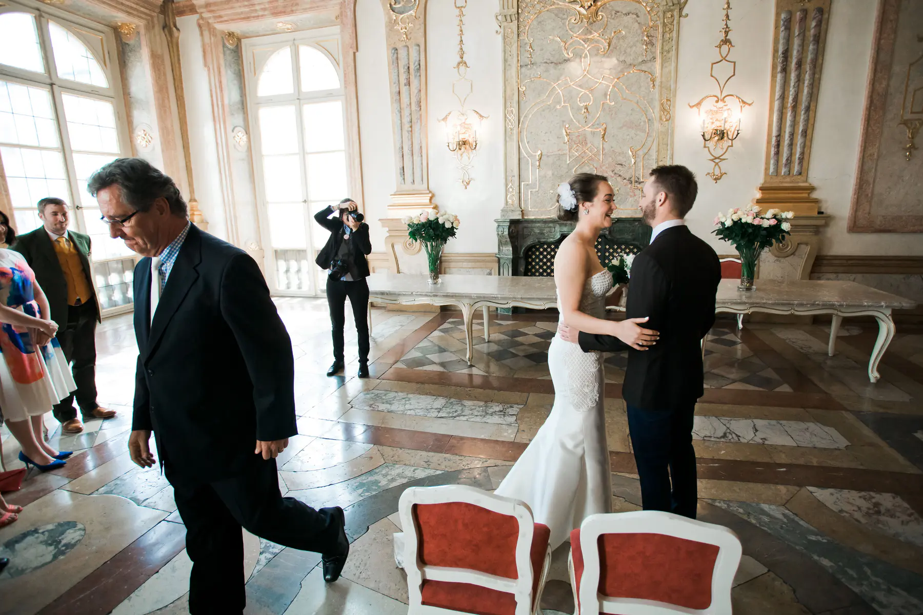 Wedding ceremony in the Marble Hall of Mirabell Palace. A wedding photographer takes pictures of a bride and groom in a beautifully decorated room.