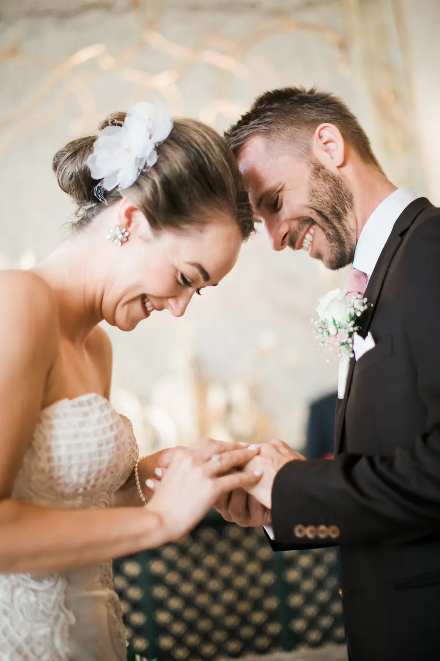 Wedding ring exchange in the Marble Hall Salzburg. A smiling bride and groom, with their foreheads touching, exchange rings during their wedding ceremony.