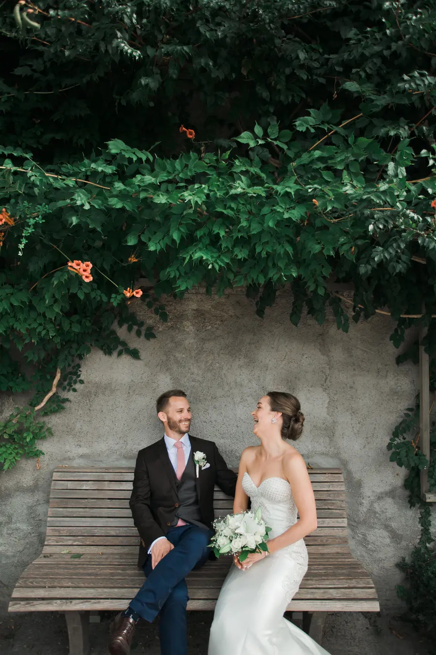 Newlyweds sitting on a classic park bench in Salzburg, enjoying a private moment amidst the greenery of Mirabell Palace.