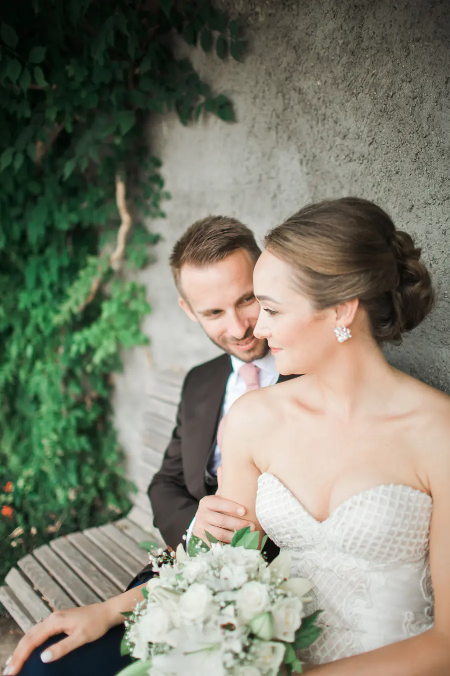 Newlyweds sitting on a classic park bench in Salzburg, enjoying a private moment