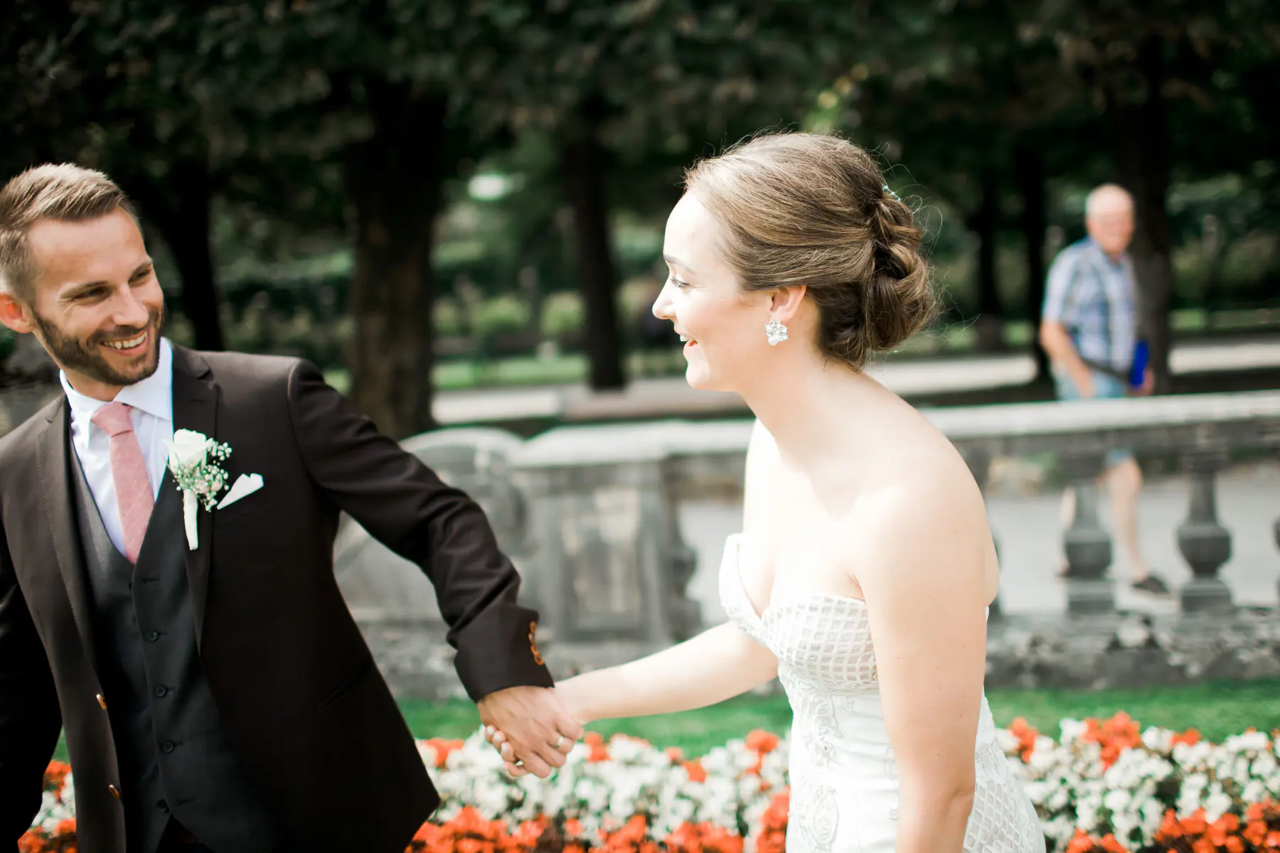 An editorial-style wedding photo featuring the couple near historic Baroque statues in the gardens of Mirabell Palace.