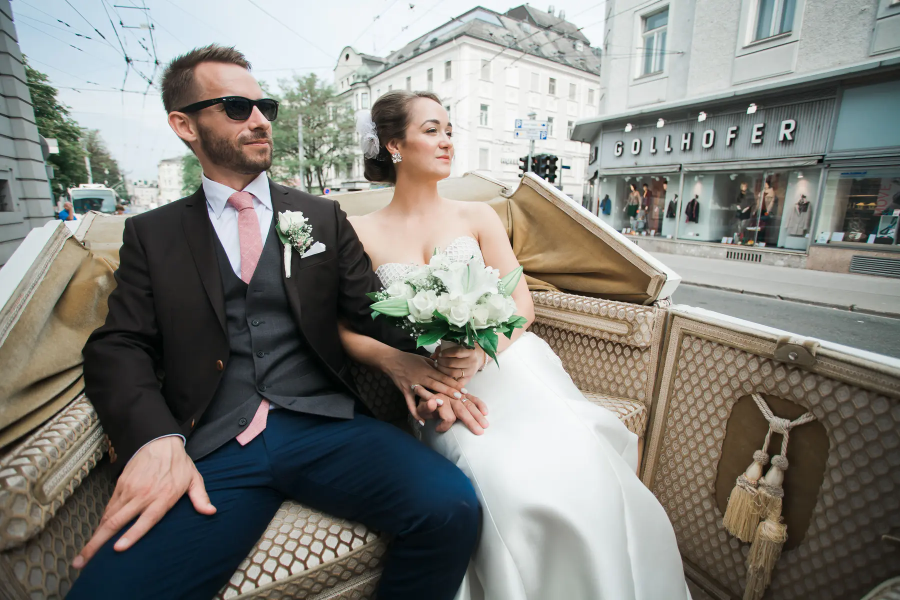 A wide storytelling frame of the wedding carriage with historic Salzburg landmarks in the background on a perfect sunny day.