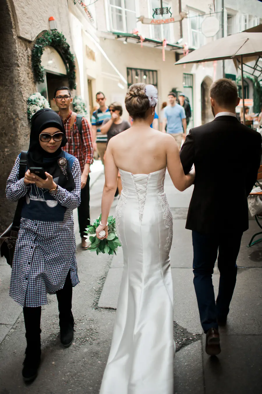 A poetic shot of the bride and groom walking away into the narrow, sunlit alleys of Salzburg's Old Town, highlighting the timeless architecture.