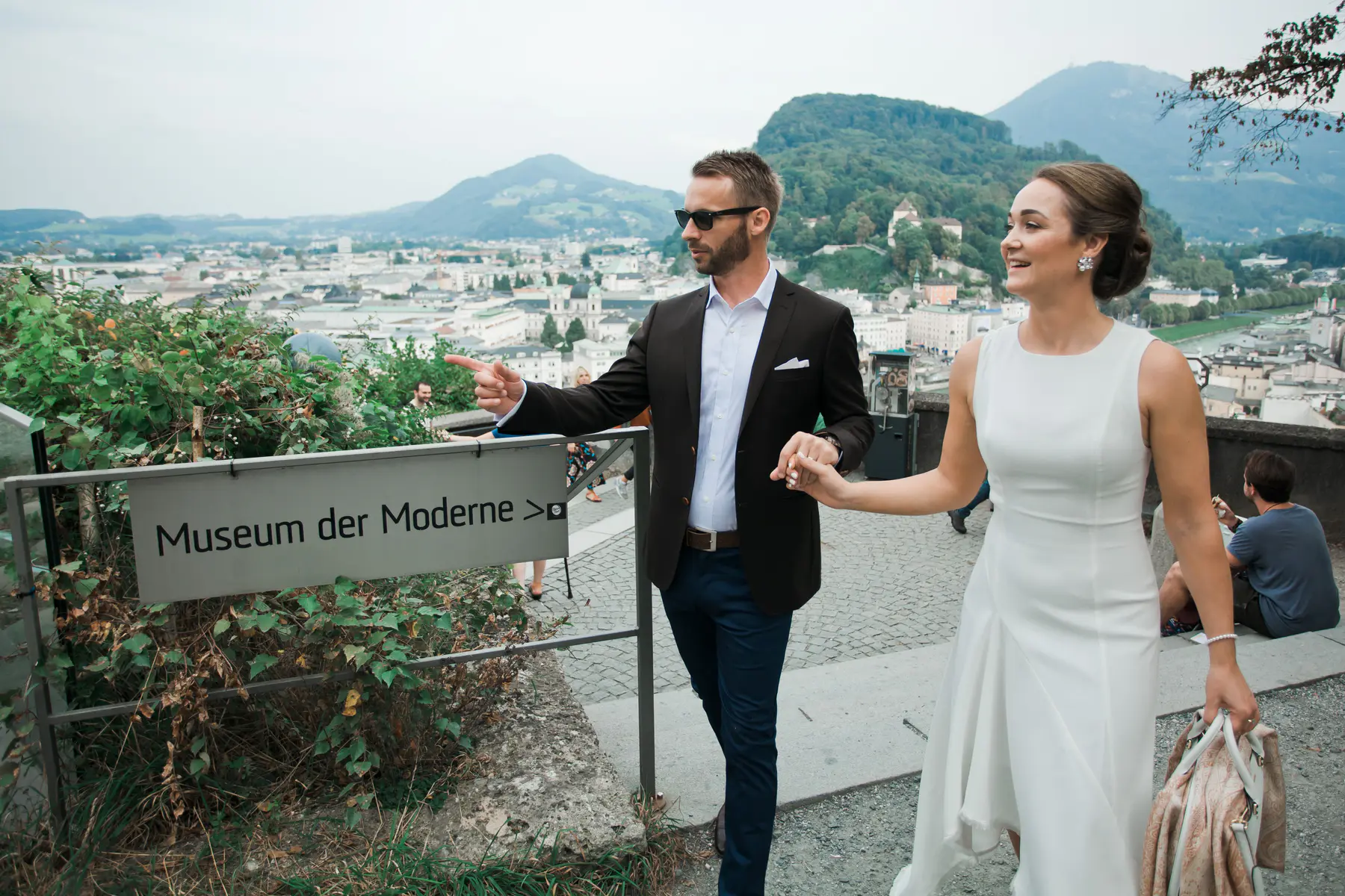 A grand shot of the bride and groom arriving at the Museum der Moderne plaza, showcasing the striking contemporary architecture against the Salzburg sky.