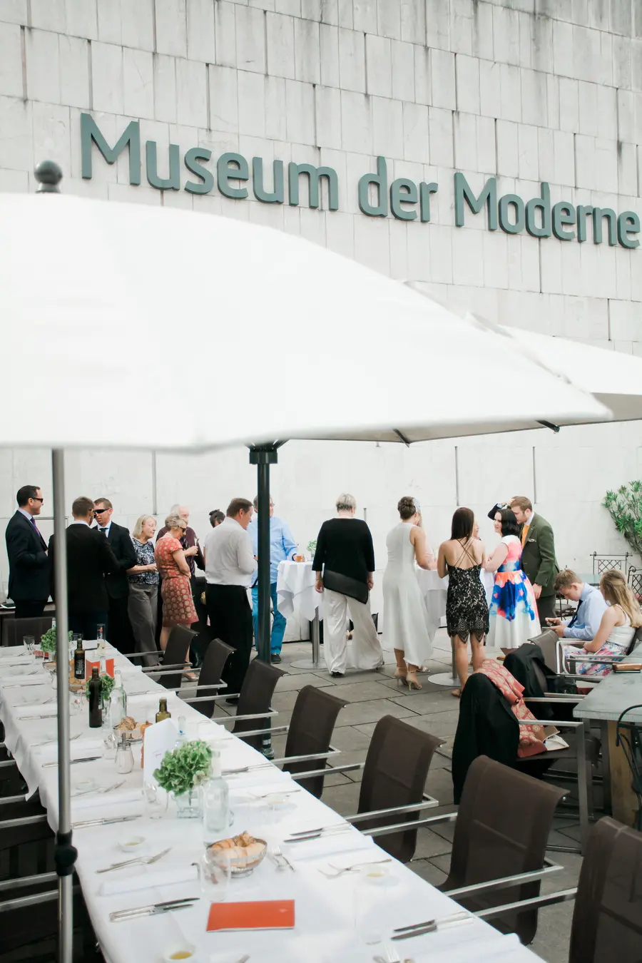 A storytelling frame capturing the wedding party and guests gathered on the museum's terrace, blending modern art vibes with a joyful celebration.