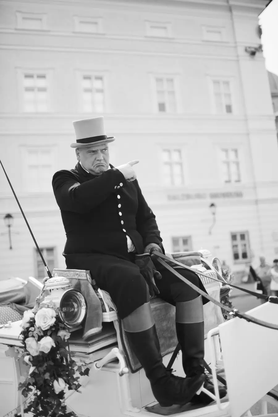 Close-up of a traditional coachman driving the wedding carriage on a bright, sunny day in Salzburg.