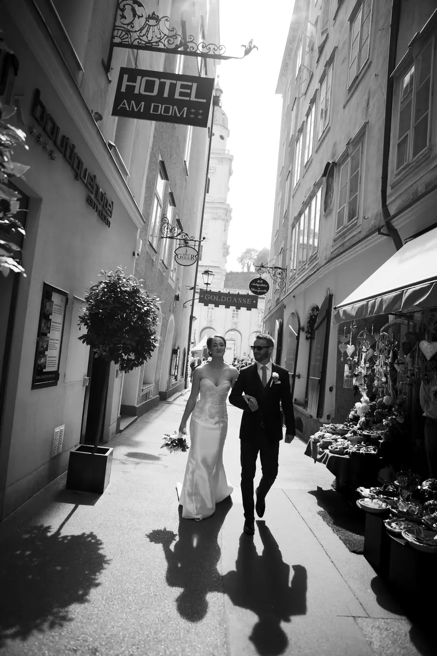 A poetic shot of the bride and groom walking away into the narrow, sunlit alleys of Salzburg's Old Town, highlighting the timeless architecture.