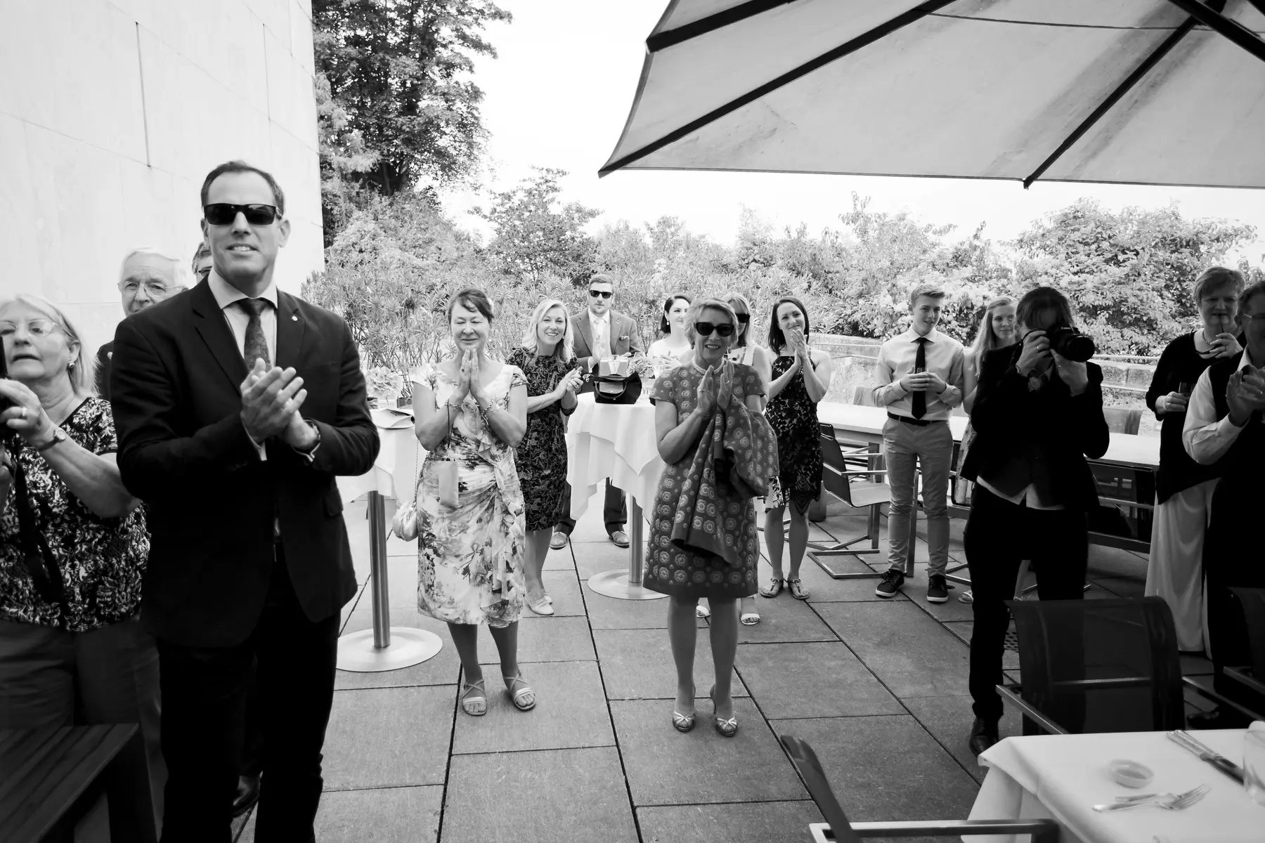 An authentic photojournalistic moment showing guests warmly welcoming and cheering for the newlyweds as they arrive for their celebration.