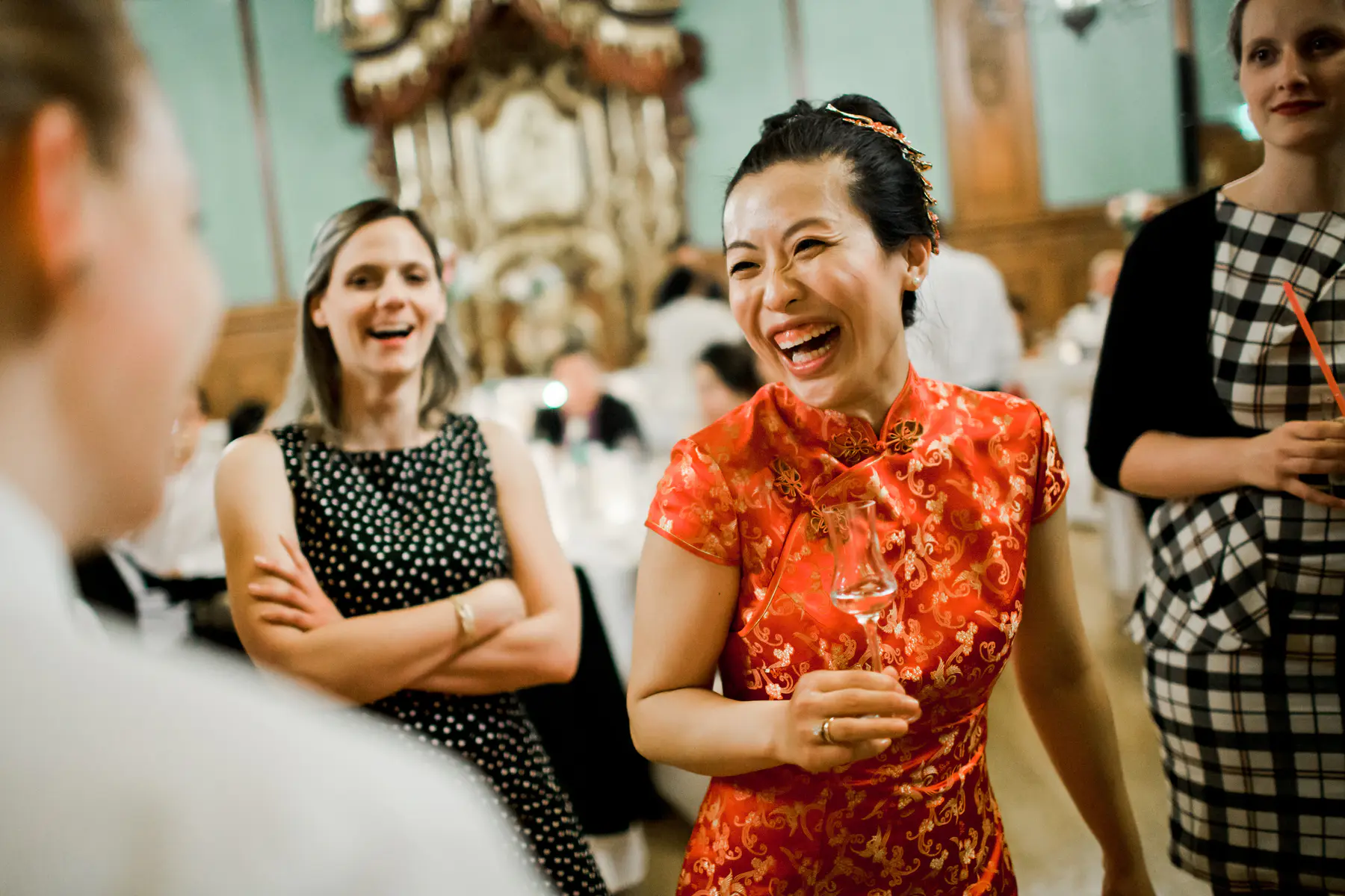 维也纳下奥地利宫 (Palais Niederösterreich) 的动人瞬间：身着传统红色礼服的新娘在晚宴中尽情欢笑。记录中国婚礼中独特的文化融合与奢华派对氛围。真实、生动的纪实摄影，捕捉最纯粹的快乐。Marek & Klára 专属艺术影像。