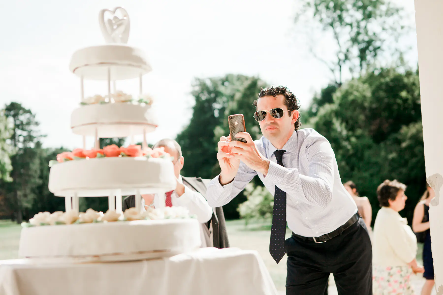 man taking picture of wedding care on his aple phone