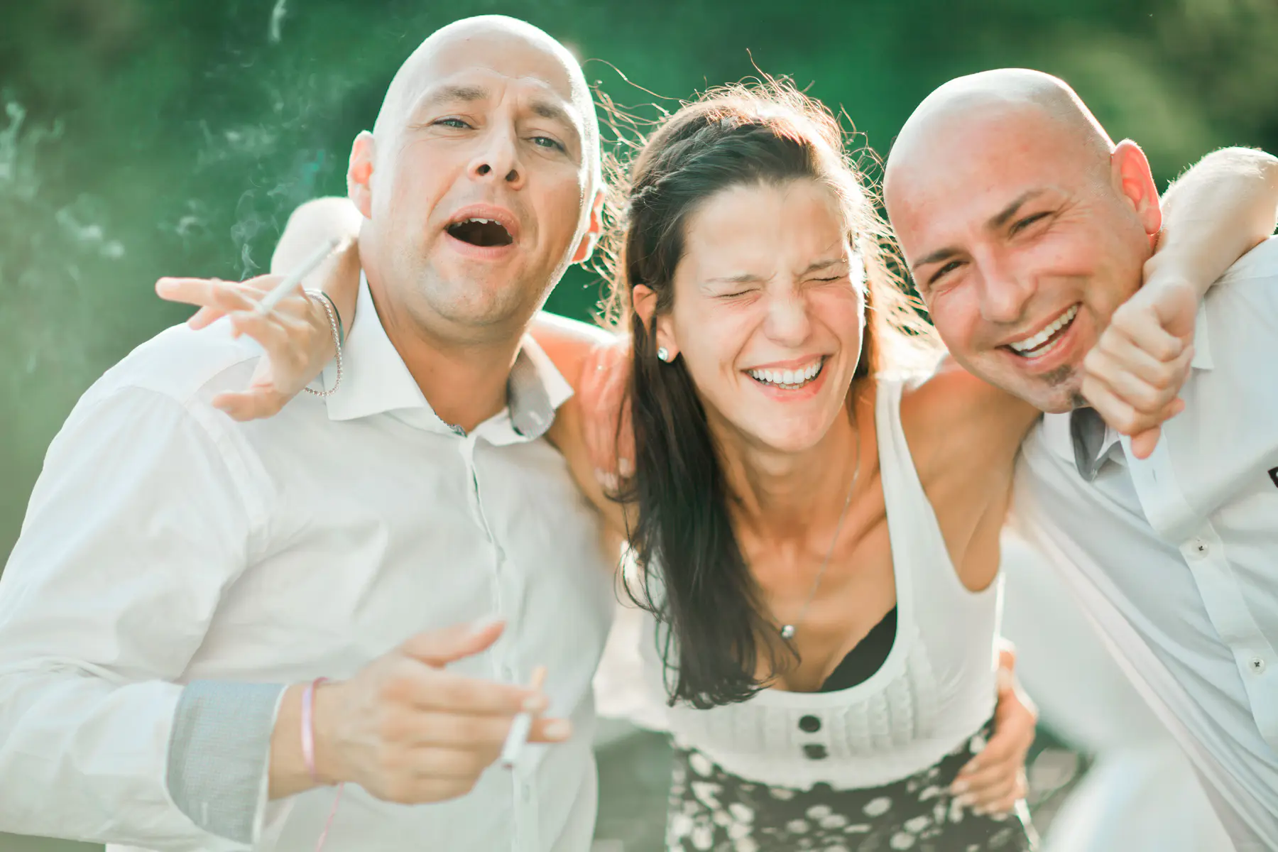 Friends laughing, smoking, and hugging outdoors