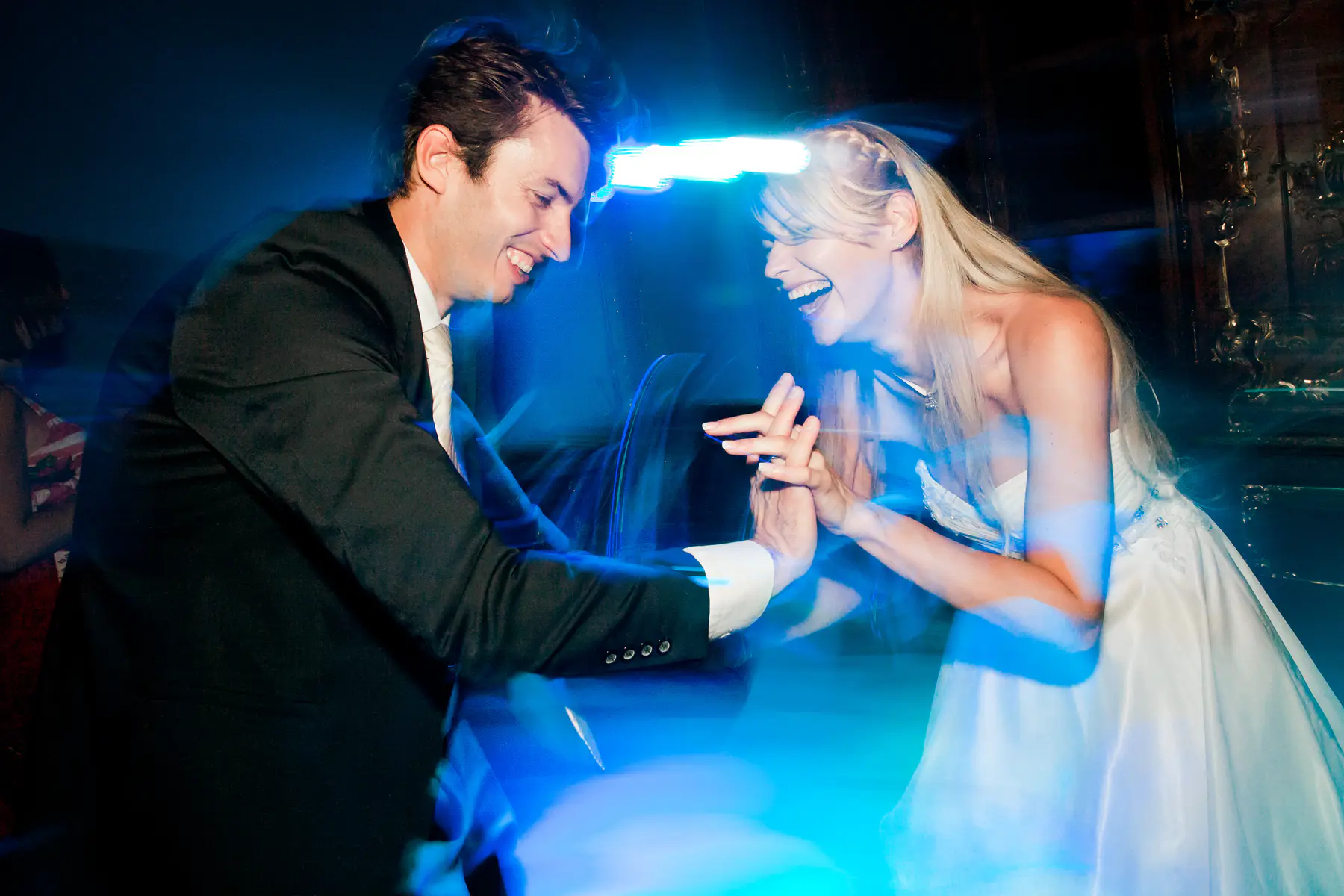 Couple dancing joyfully under blue lights.Strobist style