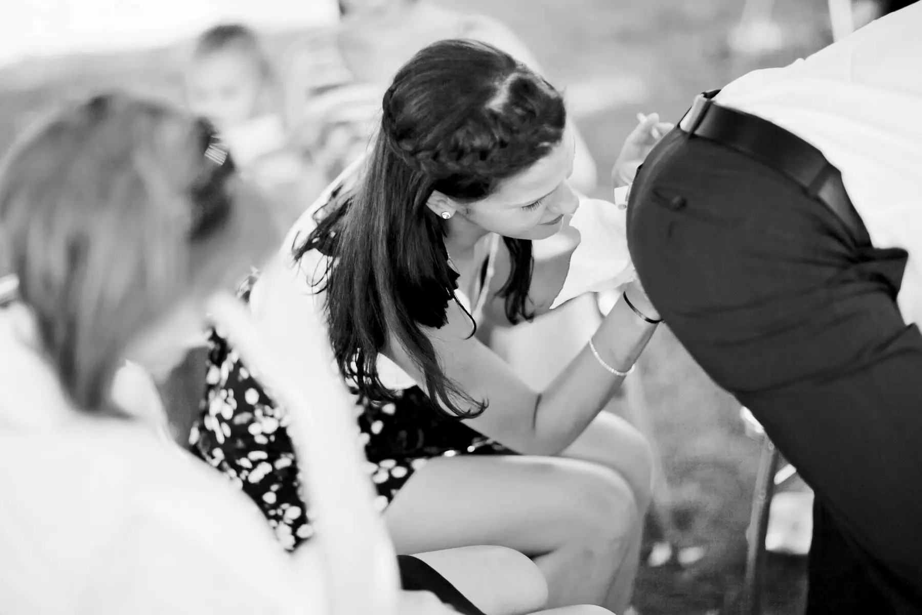 A woman in a black and white photo cleaning trouser in ass area to man