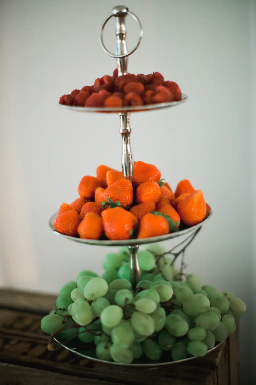 Tiered fruit stand with seasonal fruits and floral wedding decor.