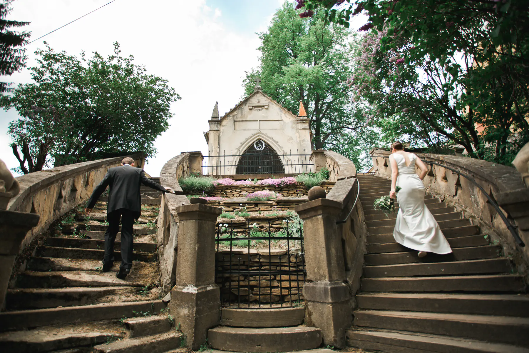 ewlyweds walking up the stone stairs towards a historic church – authentic wedding cinematography capturing a symbolic journey.