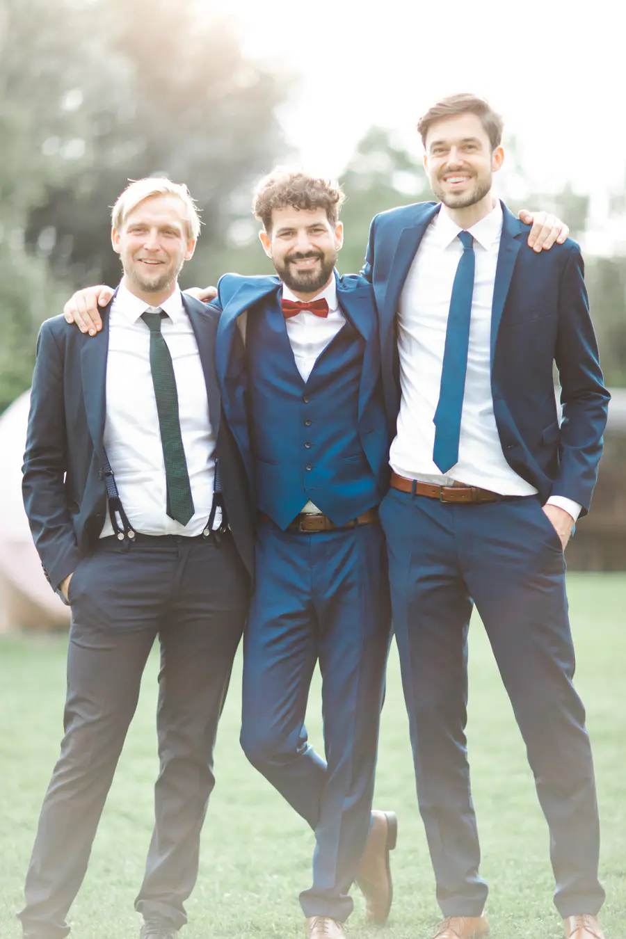Authentic wedding photojournalism Vienna – Three groomsmen in suits during golden hour, natural lifestyle photography by Stillandmotion duo.