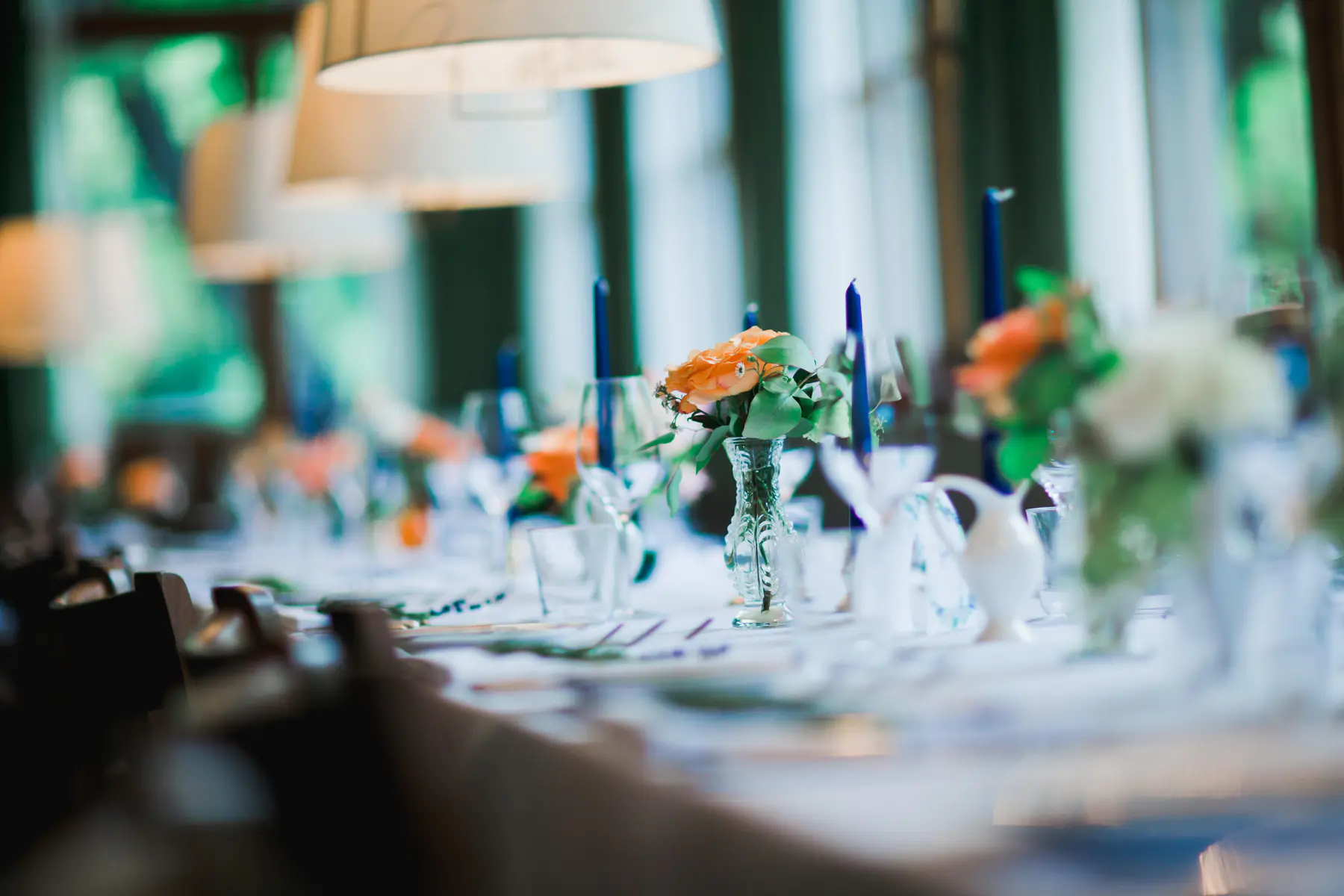 Table setting and natural light at Pfarrwirt Vienna. A close-up, out-of-focus shot shows a wedding reception table setting with elegant decor, including floral arrangements, candles, and glassware.