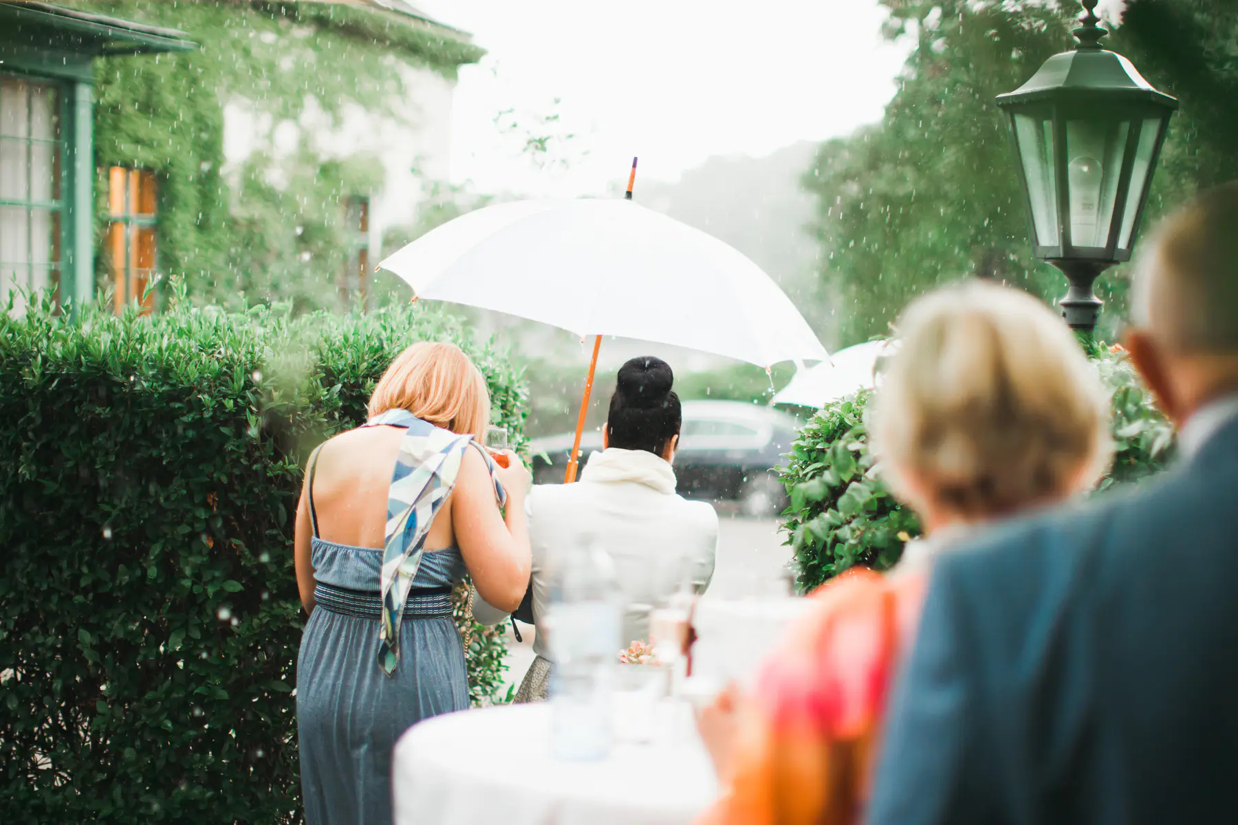 People under a white umbrella in the rain at an outdoor event.  Photojournalistic photographer Vienna