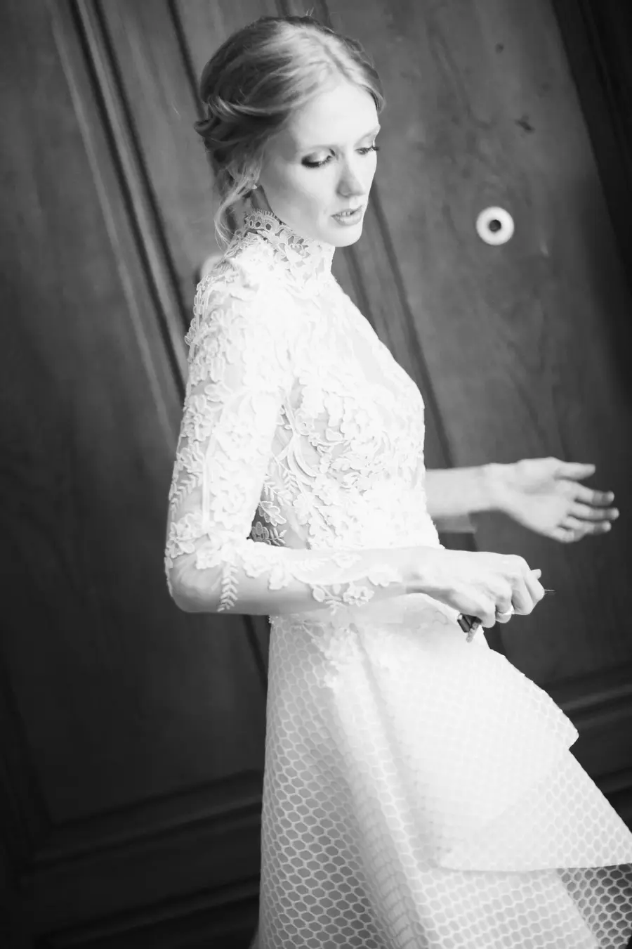 Photojournalistic photographer Vienna. A woman in a white lace wedding dress stands with her head bowed and her arms outstretched.