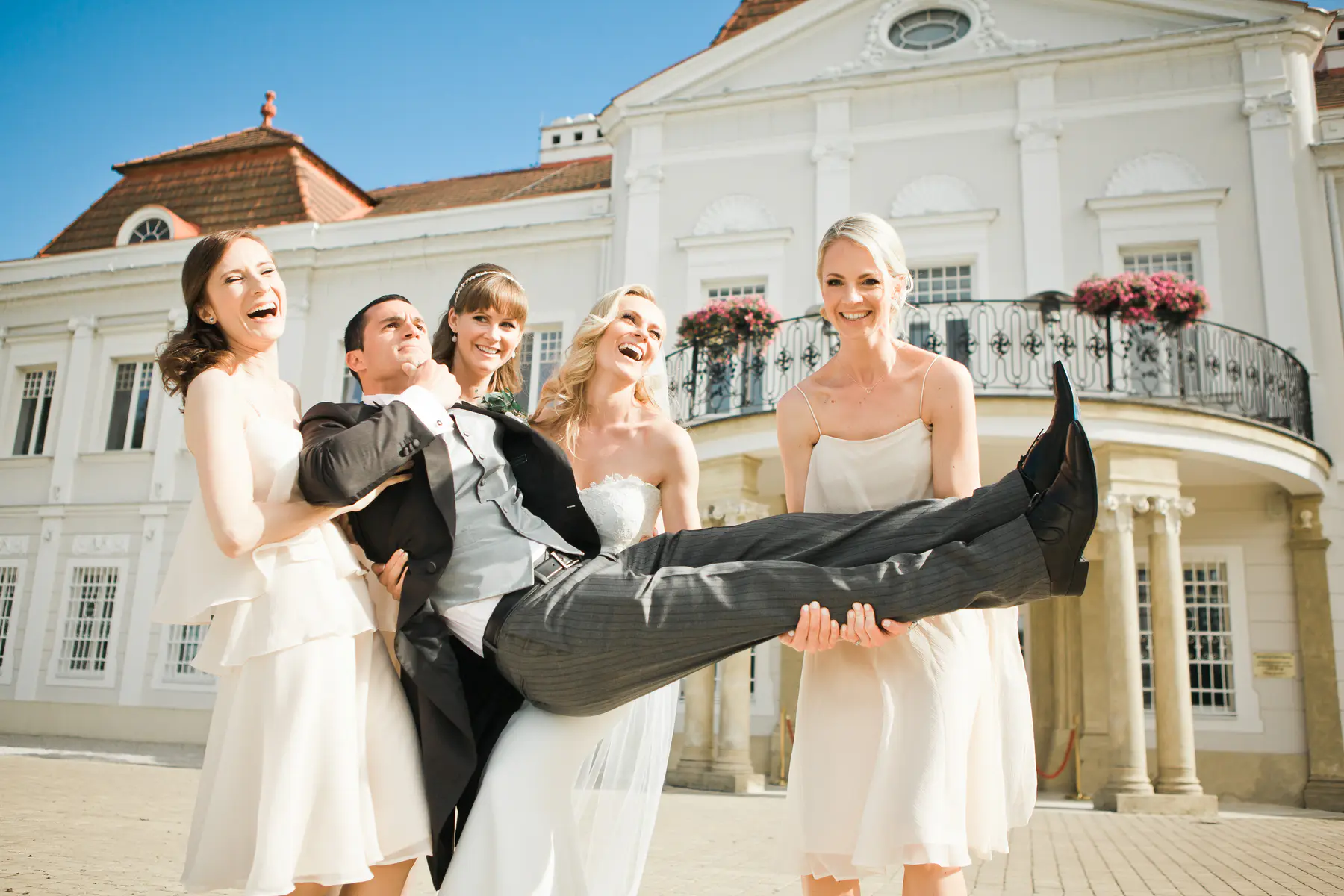 Hilarious and candid shot of bridesmaids carrying the groom in front of the historic castle.Marek and Klára wedding photography
