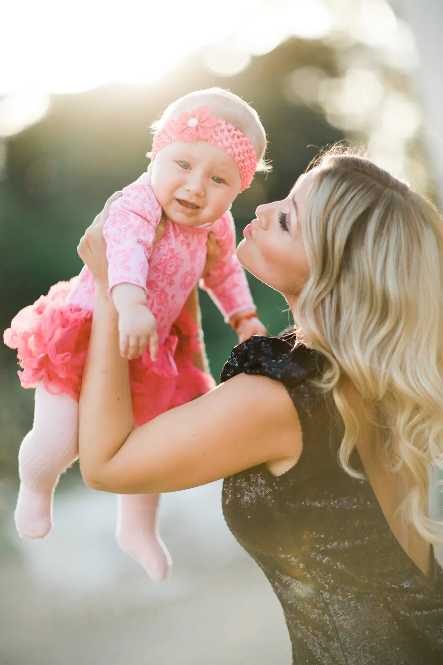 Beautiful backlit shot of a female guest holding a baby against the sun during the wedding reception.