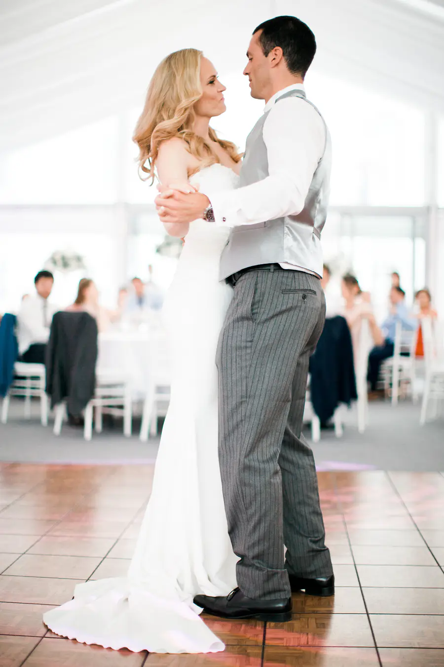 Bride and groom sharing their first dance in the white wedding tent, natural and emotional photography.