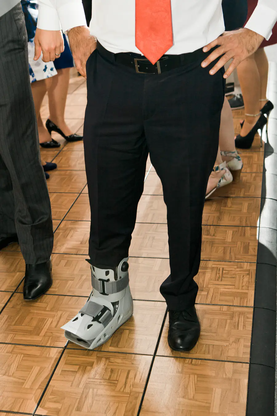 Candid and humorous shot of a wedding guest with a leg cast enjoying the party at Kastiel Tomasov.