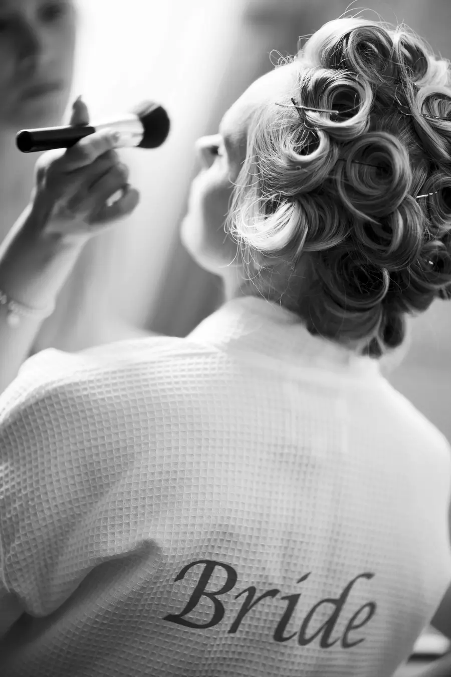 Candid moment of a bride getting her makeup done by a professional artist