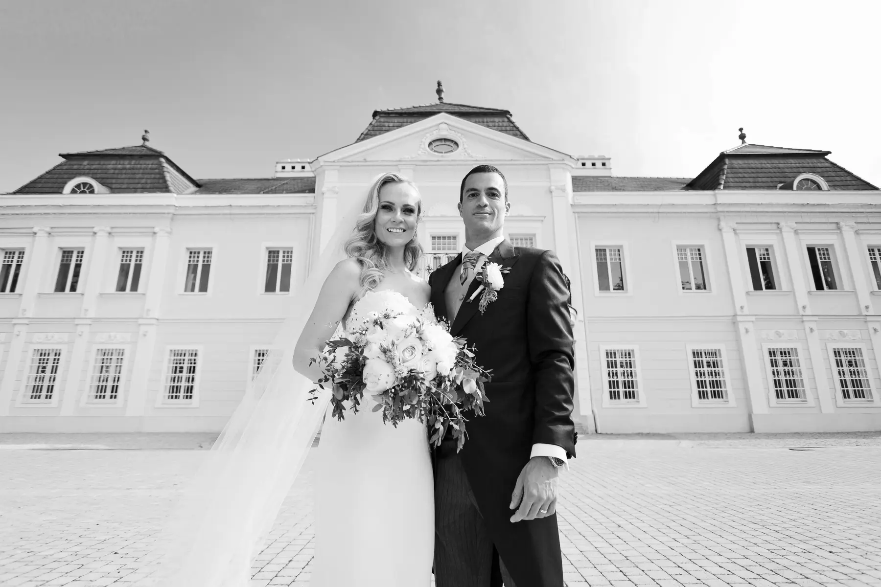 Romantic wedding portrait of the bride and groom with the grand manor house facade in the background.
