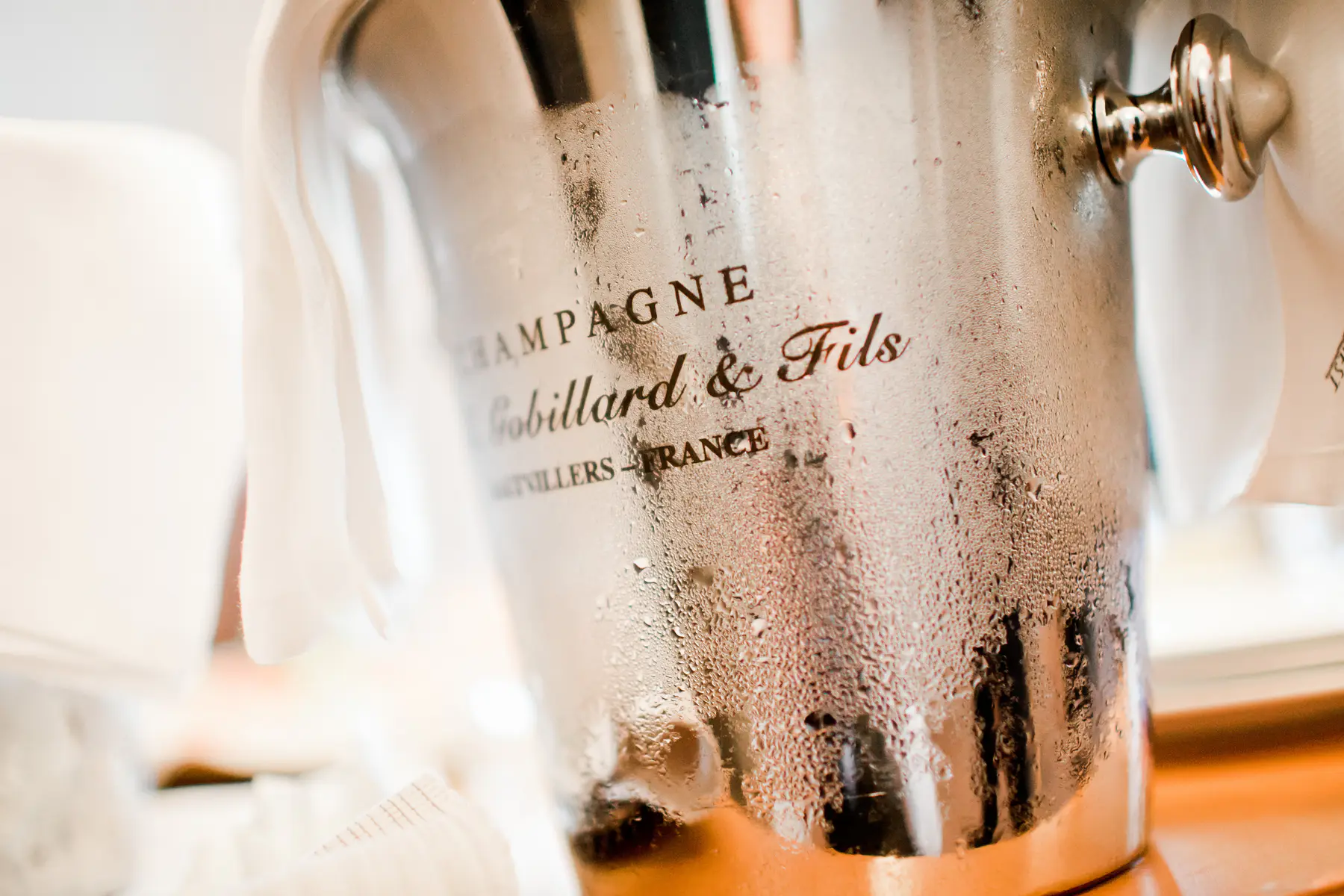 A close-up of a metallic champagne bucket covered in condensation, with the text "CHAMPAGNE Gobillard & Fils HAUTVILLERS - FRANCE" clearly visible on its side