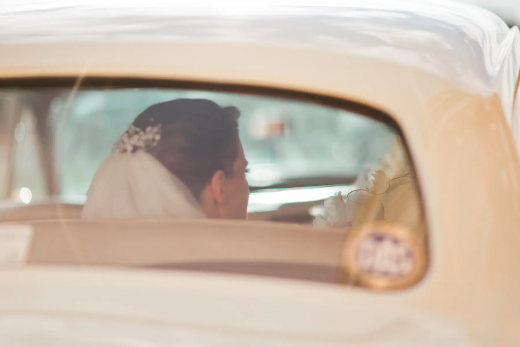 Rear view of a bride's head looking forward from the back seat of a luxury vehicle, capturing a moment of anticipation before the ceremony