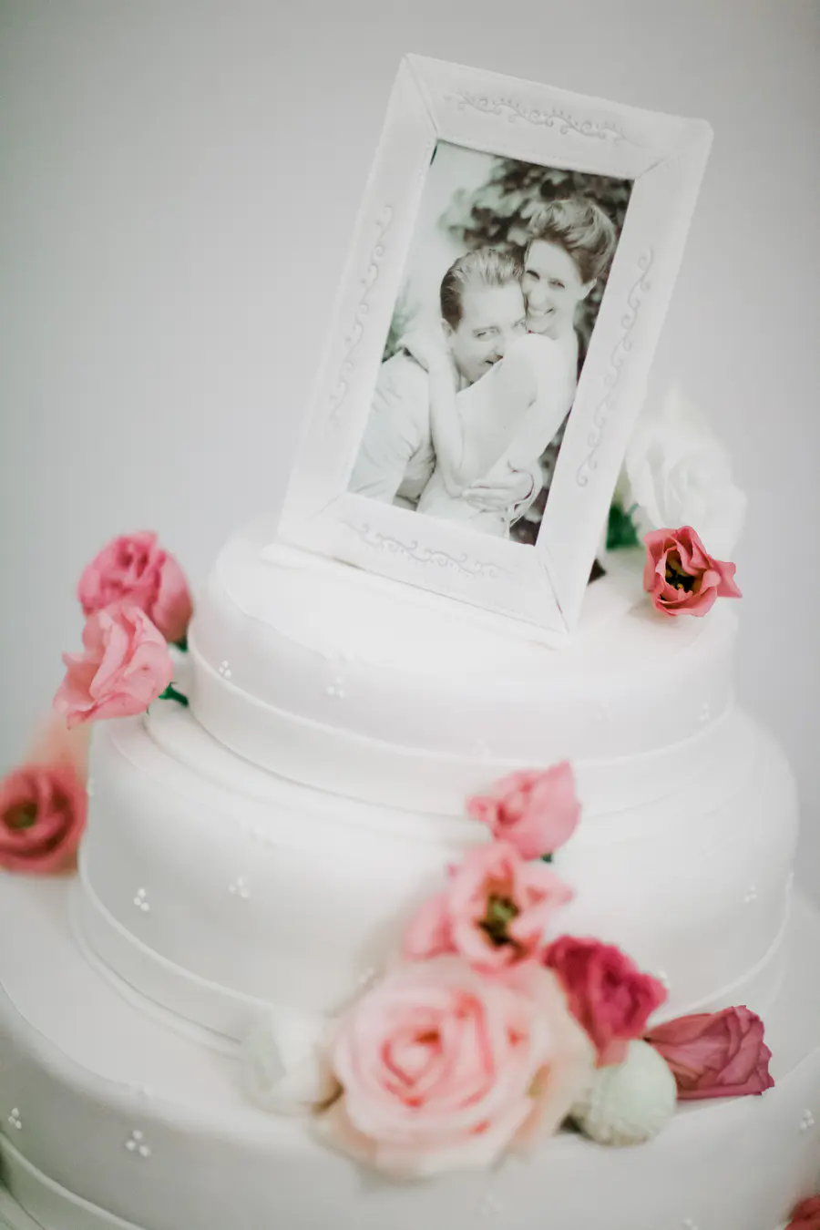  Close-up of a multi-tiered wedding cake featuring a romantic, personalized photo print of the couple as the main decoration, captured in soft focus.