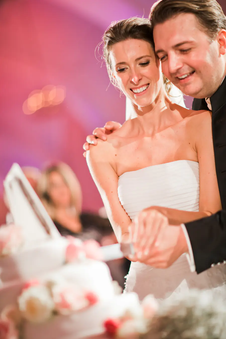 Close-up of the bride and groom's hands holding the knife to cut a beautiful floral-decorated wedding cake during the reception at Schönbrunn.