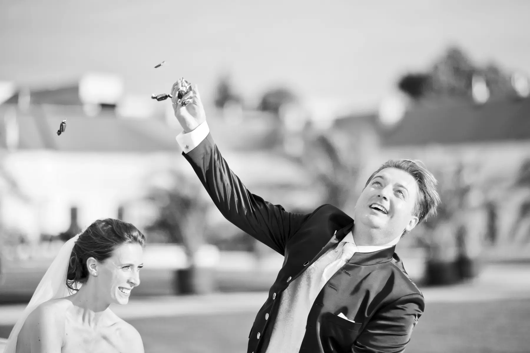 Candid shot of a bride and groom tossing a handful of candies, celebrating their wedding day with guests