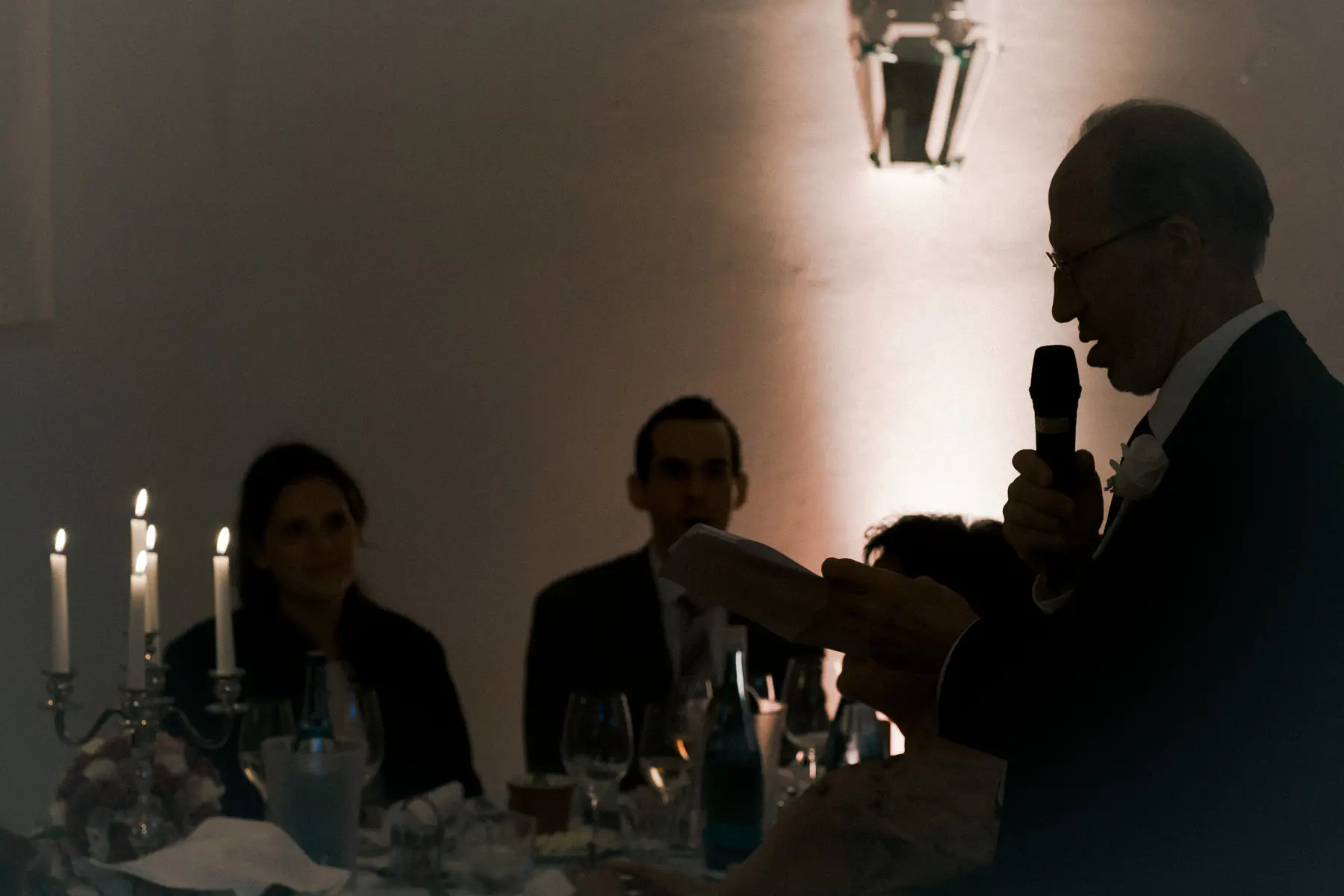 Elderly man having wedding speeches during dinner reception, reading from papers