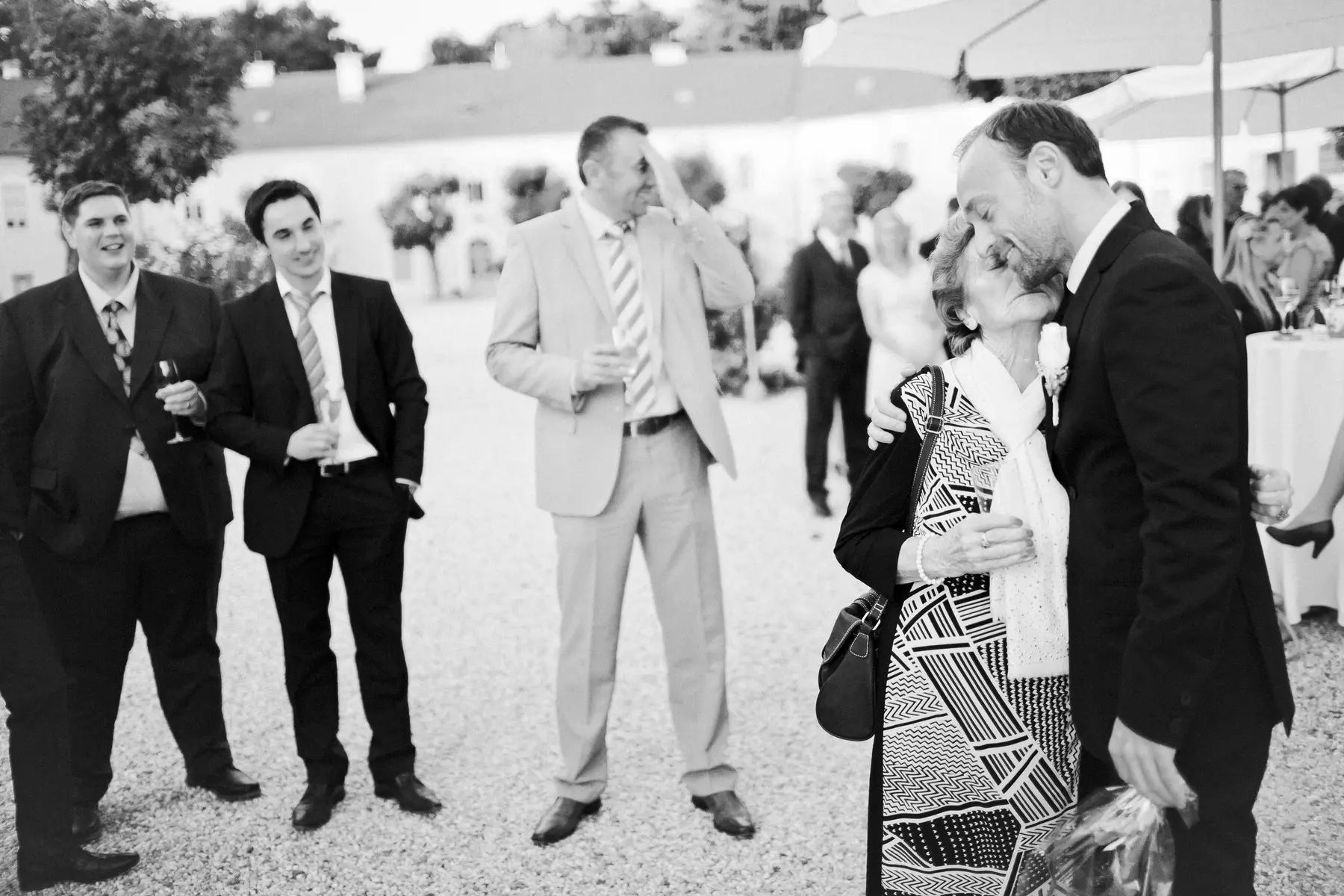 Man kisses an his mam at a formal outdoor wedding.